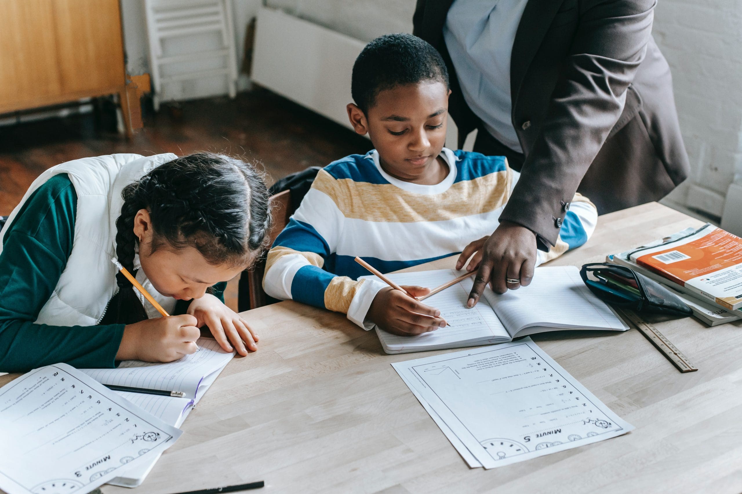 Woman helping two younger children with their schoolwork